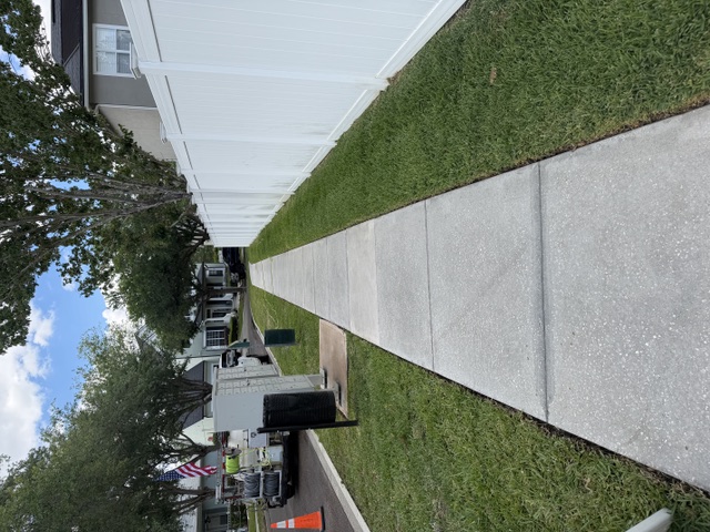 Clean concrete sidewalk running beside a bright white vinyl fence