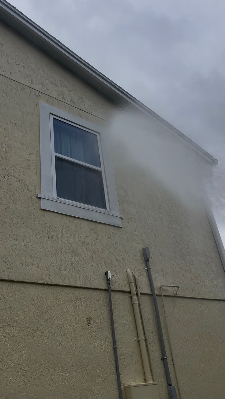Clean stucco wall and window after house soft washing
