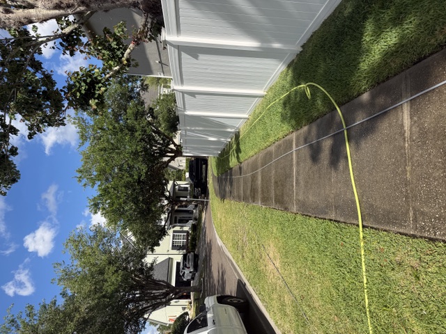 Sidewalk and white vinyl fence during cleaning with the hose laid out
