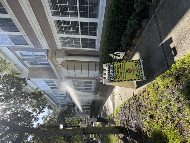 Row of townhomes being soft washed beside an Orlando House Washing caution sign